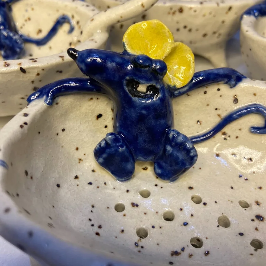 Detalhe do ratinho azul de touca amarela, deitado na banheira de cerâmica